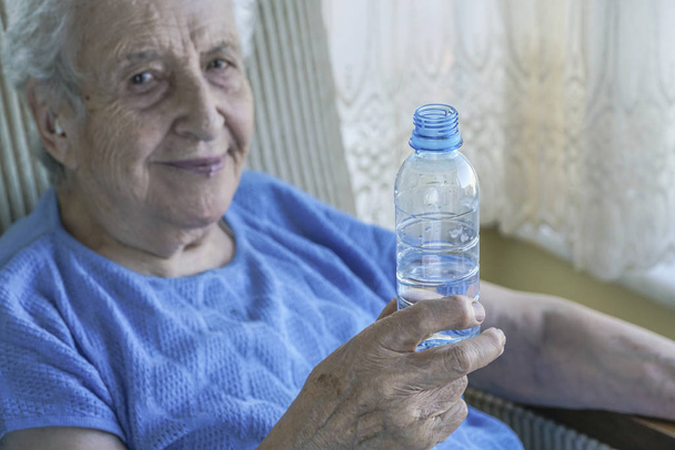 Una encantadora mujer mayor sosteniendo una botella de agua potable
 - Foto, imagen