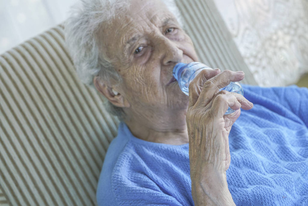 Uma adorável senhora sênior bebendo água de uma garrafa
 - Foto, Imagem