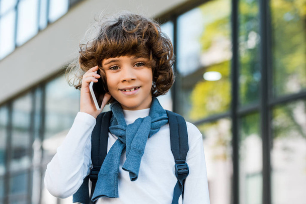 cute preteen schoolboy with backpack talking by smartphone and smiling at camera - Foto, Imagem