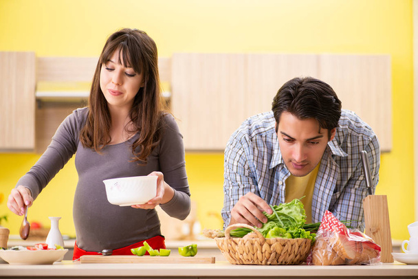 Man and pregnant woman preparing salad in kitchen  - Фото, зображення