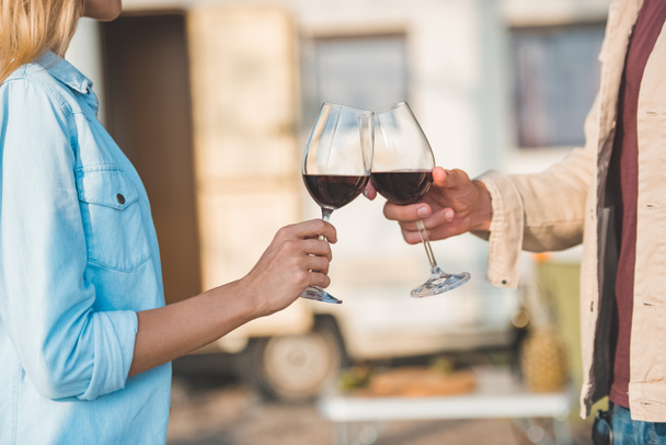 vista ritagliata di coppia clinking con bicchieri di vino rosso vicino camper
 - Foto, immagini