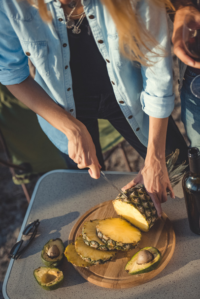 cropped view of girl cutting pineapple on wooden board - Foto, Bild