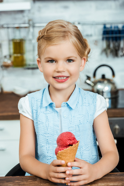 cute happy kid holding delicious sweet ice cream cone and smiling at camera   - Photo, Image