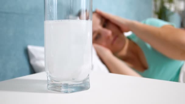 Lähikuva hidastettuna video aspiriini tabletti liuottamalla lasilliseen vettä yöpöydälle
 - Materiaali, video
