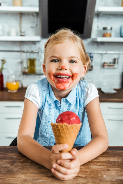 adorable happy child holding delicious ice cream cone and smiling at camera - Foto, afbeelding