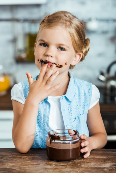 carino bambino mangiare delizioso cioccolato diffusione e guardando la fotocamera
  - Foto, immagini