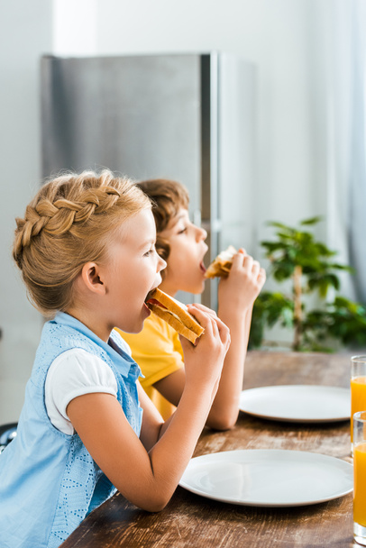 side view of cute little children eating tasty sandwiches - Фото, зображення