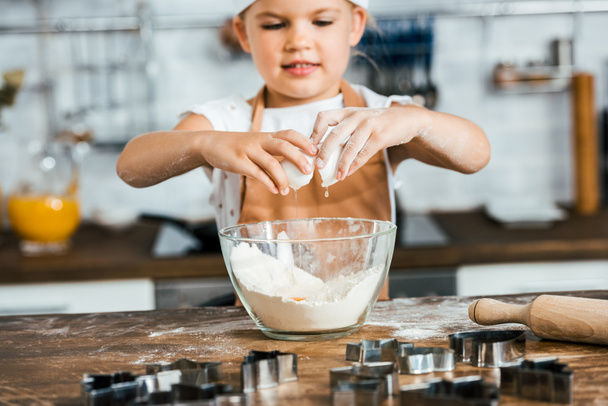 lindo niño sonriente en delantal preparando masa para galletas
 - Foto, imagen