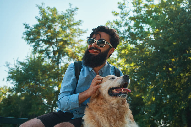 Człowiek i pies, zabawy, gry, dzięki czemu śmieszne twarze podczas odpoczynku w parku. Życie jest piękne, najlepsi przyjaciele koncepcja. - Zdjęcie, obraz