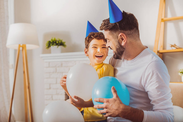 Merry charming boy and man having fun with balloons - Фото, изображение