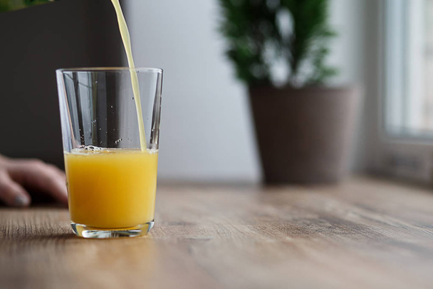 A glass of juice from the morning, she pours the juice of orange - Фото, изображение