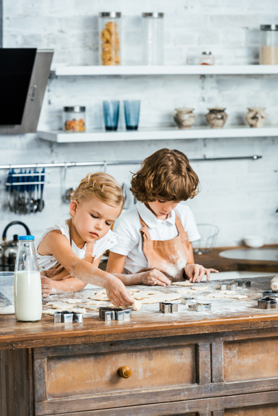adorable little children in aprons preparing cookies together - Foto, Imagen