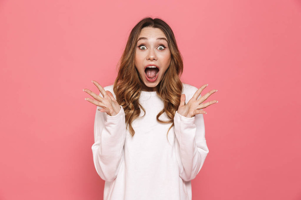 Portrait of an excited young casual girl screaming isolated over pink background - Fotografie, Obrázek