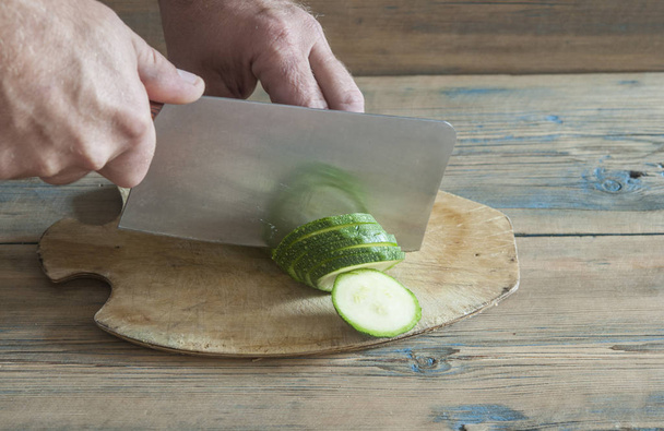 Lo chef usa un coltello da cucina per tagliare zucca e zucchine su un tagliere di legno
 - Foto, immagini