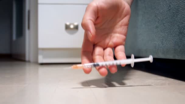 家の床の上に落ちて注射器を持っている女性の手のクローズ アップのスローモーション映像。薬物、麻薬中毒の概念 - 映像、動画