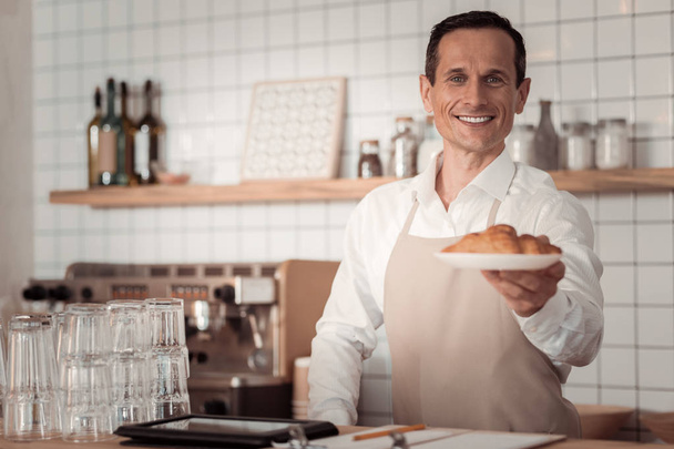 Happy delighted man holding a croissant - Valokuva, kuva