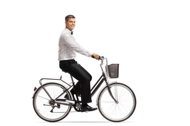Handsome young man in a tux riding a bicycle isolated on white background - Фото, зображення
