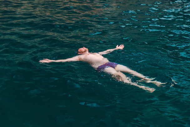 człowiek, pływanie tyłu w przejrzyste morze niebieski wody. letnie wakacje - Zdjęcie, obraz