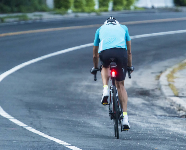 Ένας αθλητής είναι σε μια κατάρτιση βόλτα με το ποδήλατό του δρόμου αγωνιστικά νωρίς το πρωί. - Φωτογραφία, εικόνα