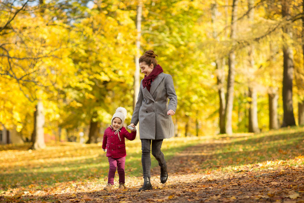happy mother and little daughter at autumn park - Photo, Image
