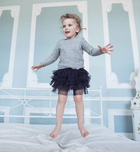 happy five year old girl jumping on the bed - 写真・画像