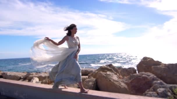 Elegáns nőt walking-a köves strand ruha. Nyári modell élvezze tengeri táj - Felvétel, videó
