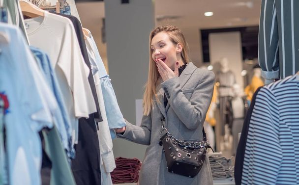 Happy girl in trendy boutique to choose cheap clothes on sale, low price  - Фото, зображення