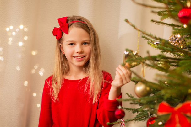 happy girl in red decorating christmas tree - Fotoğraf, Görsel