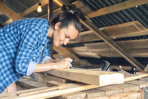 Vue latérale d'une femme charpentier dessine sur la ligne de coupe de conseil en bois
 - Photo, image