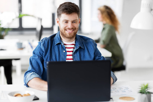 smiling creative man with laptop working at office - Photo, image