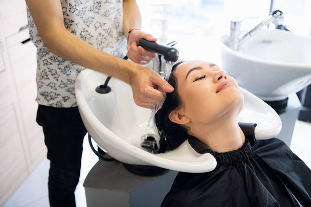 Kadeřnický salon. Krásná bruneta žena při mytí vlasů - Fotografie, Obrázek