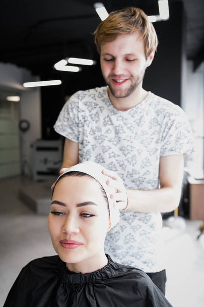 Salon fryzjerski Zawijanie ręcznik na głowie klientów. Brunetka kobieta wychodzi leczenie włosów w salonie fryzjerskim. - Zdjęcie, obraz