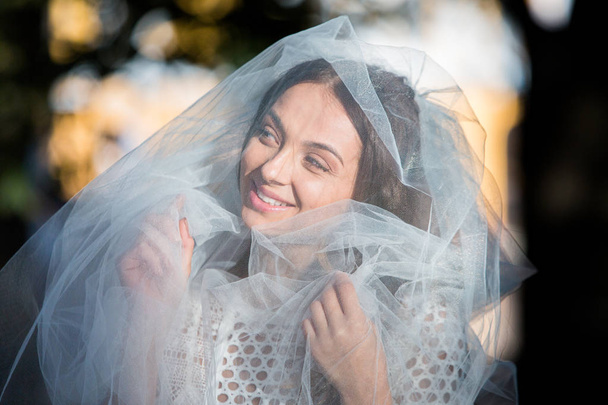 Fashion photo of a beautiful bride. Happy bride in a stylish white dress. Stylish wedding bride with bouquet and amazing modern dress. - Fotó, kép