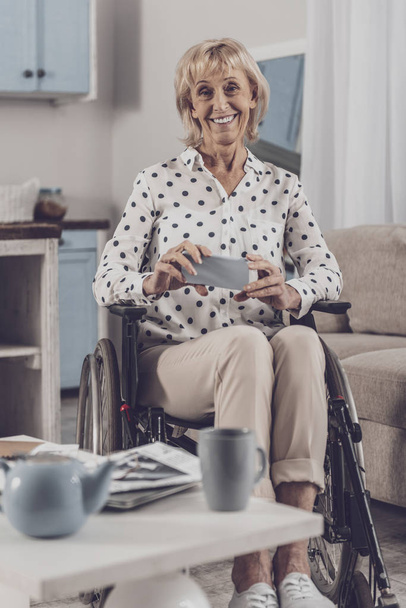 Tea time. Disabled smiling woman feeling extremely relieved while enjoying tea time with her lovely family - Fotografie, Obrázek