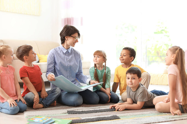 Young woman teaching little children indoors. Learning by playing - Photo, Image