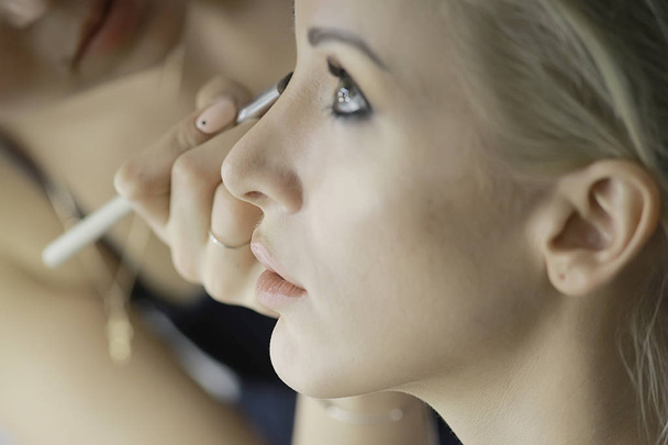 professional make-up in the beauty salon.  Master doing make-up for beautiful model in the salon - Foto, Bild