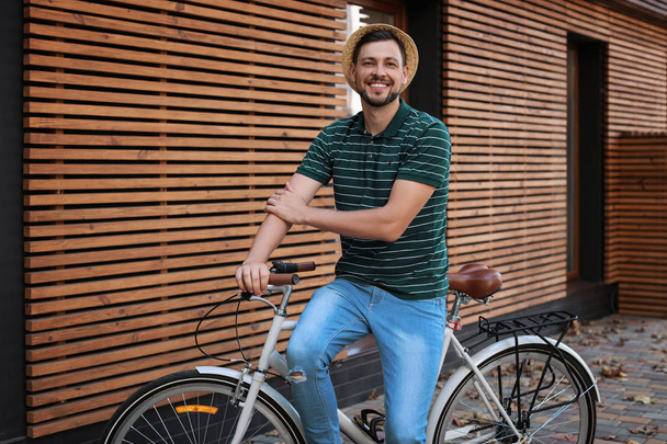 Man with bicycle on street near wooden wall - Valokuva, kuva