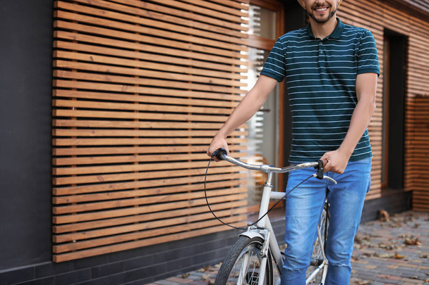 Man with bicycle on street near wooden wall, closeup - Foto, afbeelding