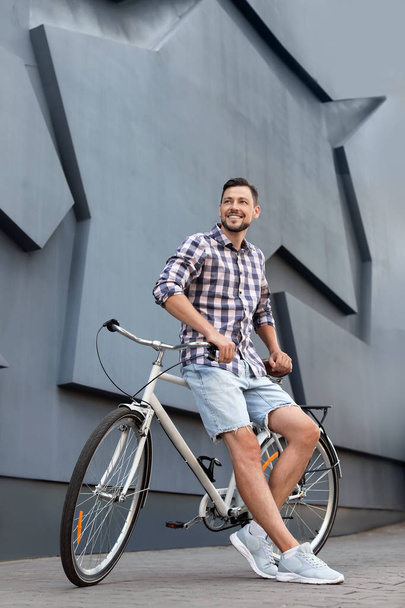 Man with bicycle on street near gray wall - Zdjęcie, obraz