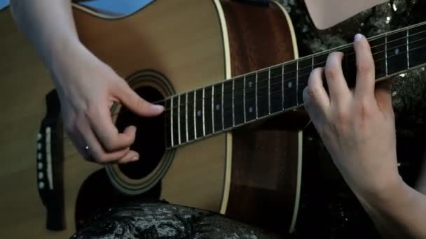 Primo piano delle mani di una ragazza che suona una chitarra acustica. Concentrati sulle dita che bloccano gli accordi sulla tastiera. Giorno di musica
. - Filmati, video