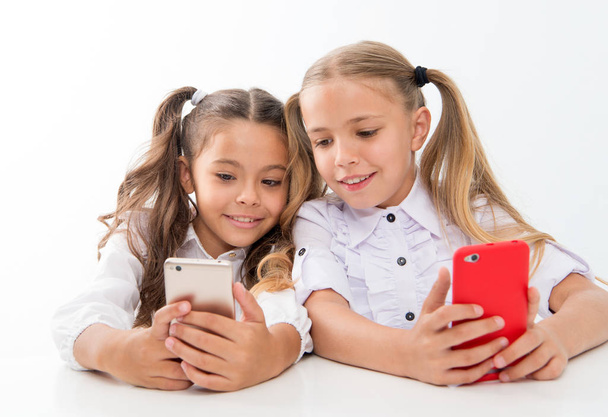 Online life concept. Schoolgirls cute pupils use smartphones big diagonal screen to check social networks. Check it out. Send message to friend. Online communication messaging. Game application - Photo, image