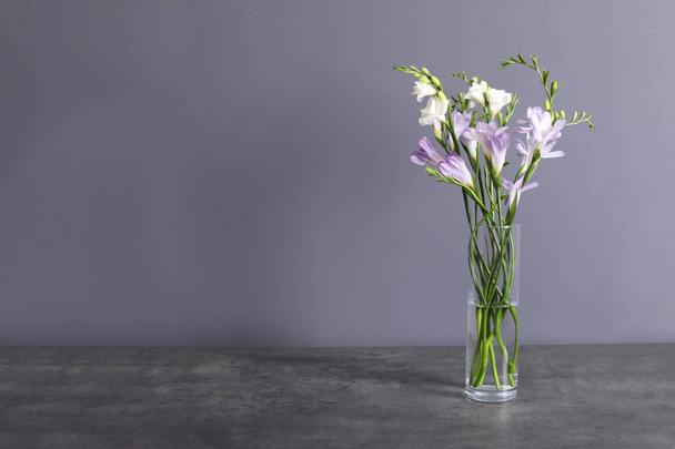 Beautiful fragrant freesia flowers in vase and space for text on color background - Fotoğraf, Görsel