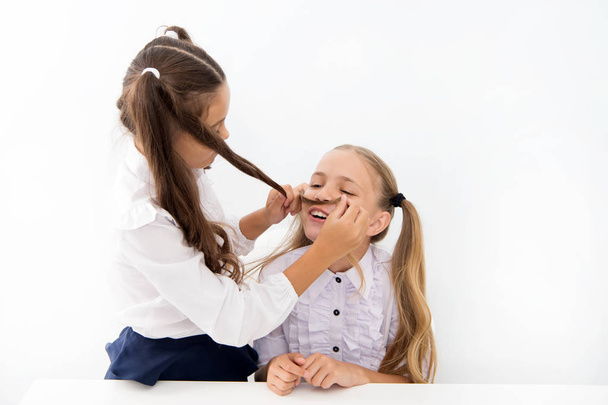 Girls make mustache with long hair. Lets imagine you were boy. Girl cheerful playful mood play with hair as mustache. Masculinity and femininity concept. Hairstyle fashion. Schoolgirls tidy uniforms - Zdjęcie, obraz