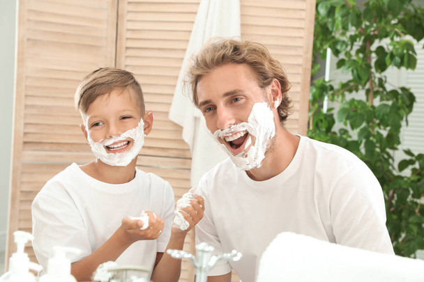 Father and son shaving together on color background - Fotoğraf, Görsel