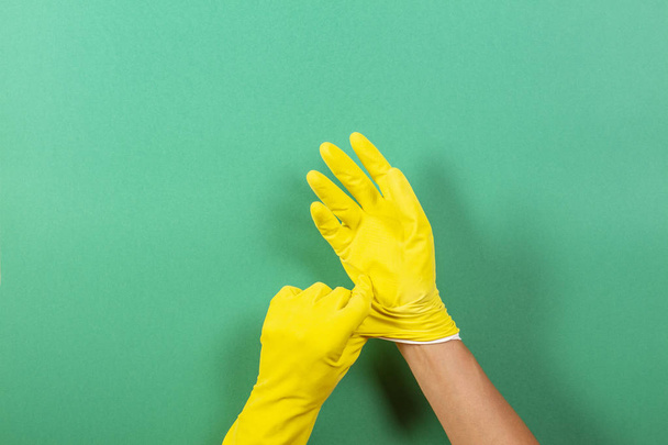 Τα χέρια βάζοντας στα κίτρινα λαστιχένια γάντια - Φωτογραφία, εικόνα