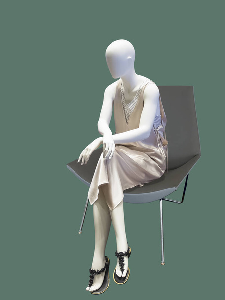 weibliche Schaufensterpuppe sitzt auf Sessel, isoliert auf grünem Hintergrund. keine Markennamen oder Copyrightobjekte. - Foto, Bild