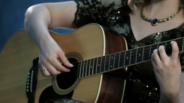 Bir kızın boynundaki kolye ile akustik gitar çalar. Sağ el dizeleri dokunursa, sol el akorları klavye üzerinde tutar. Arka planda duman. Gün müzik. - Video, Çekim