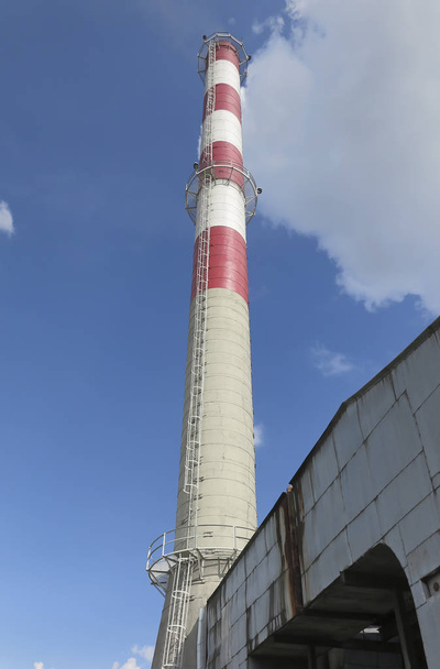 Korkea puna-valkoinen betoni teollisuuden savupiippu taivasta vasten
 - Valokuva, kuva