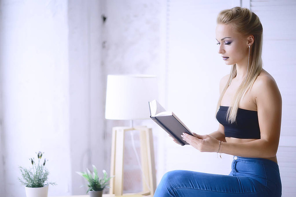 beautiful young blonde woman reading book at home - Фото, зображення