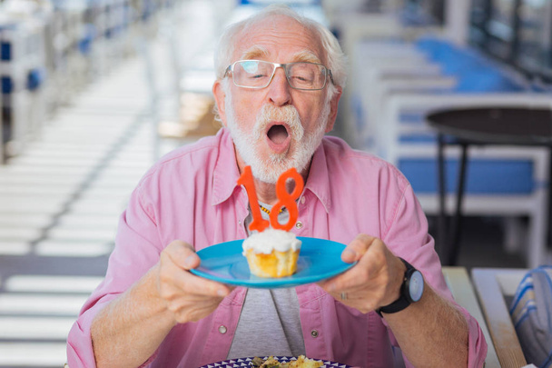 Delighted senior man holding a plate with cake - Foto, Imagen